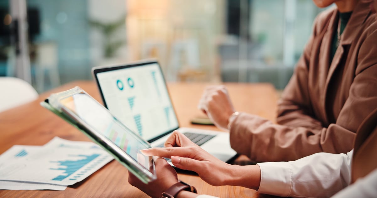 Equipo revisando gráficas financieras y resultados de ingresos en una tableta durante una junta de análisis
